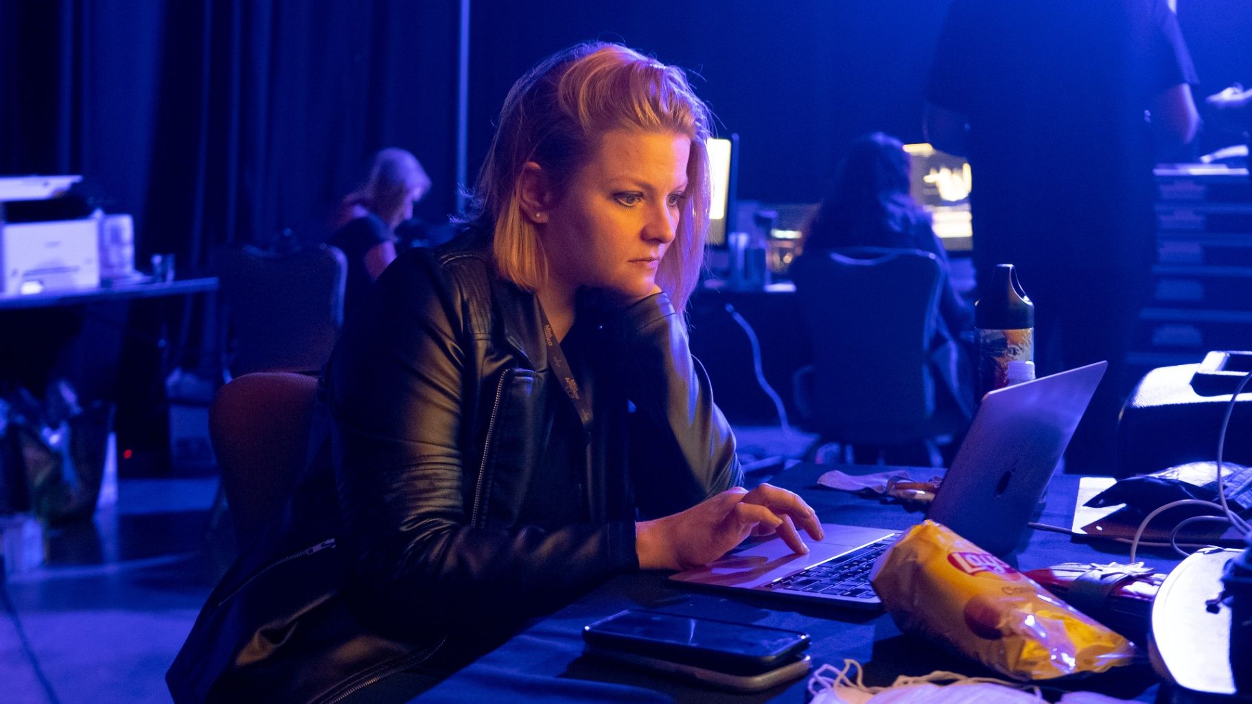 Susan working at a laptop in blue stage light
